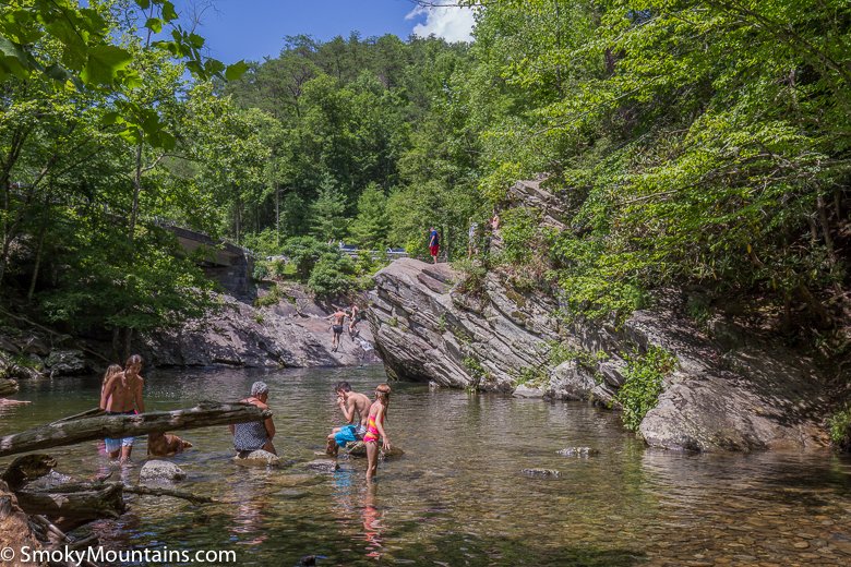 people in a river with gray rock cliffs in background