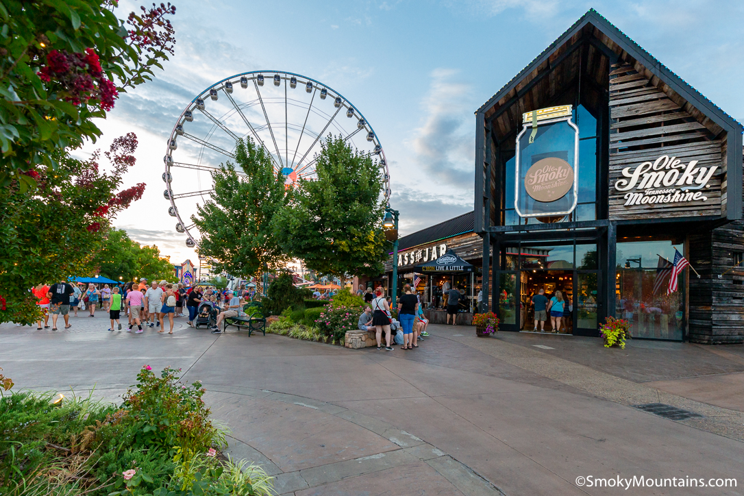 A wide shot of Ole Smokey Tennessee moonshine's outside view with ferris wheel and Nashville tourists.