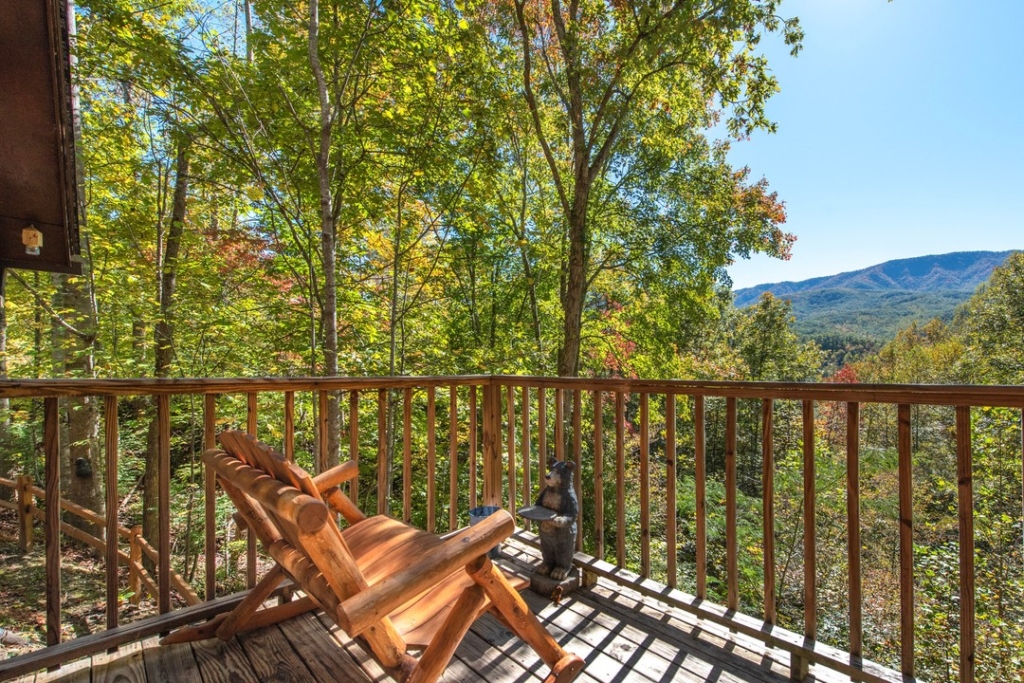 wooden chair sitting on balcony with wooden railing and mountains in the background