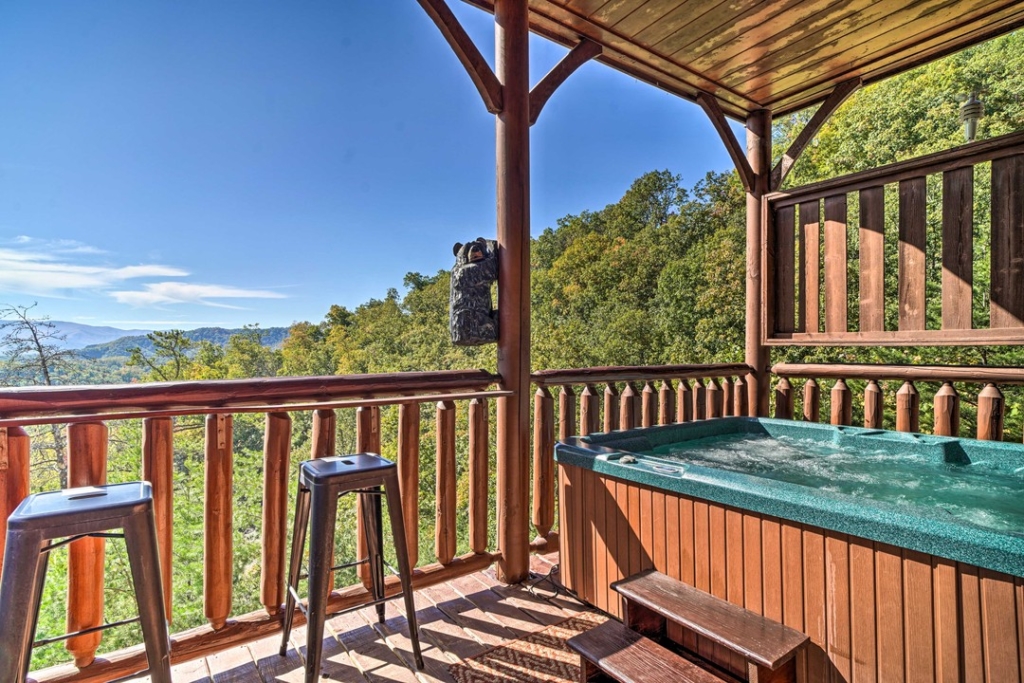 green and wooden hot tub on balcony overlooking the smoky mountains with clear blue skies