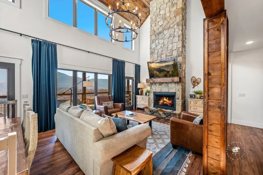 living room with stone fireplace and beige couches with blue curtains