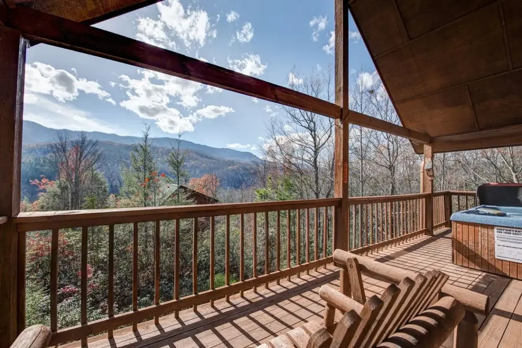 wooden chair and private hot tub on balcony overlooking other cabins and fall foliage