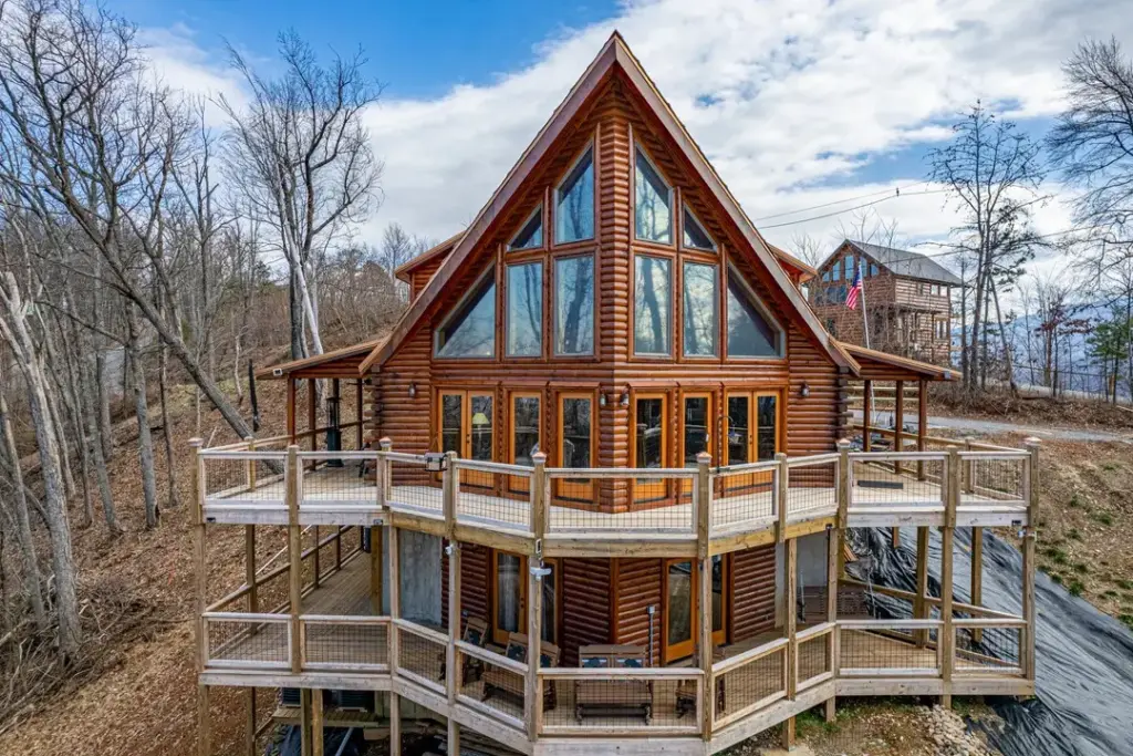 exterior of wooden cabin home with two tier balcony and leaveless trees surrounding it