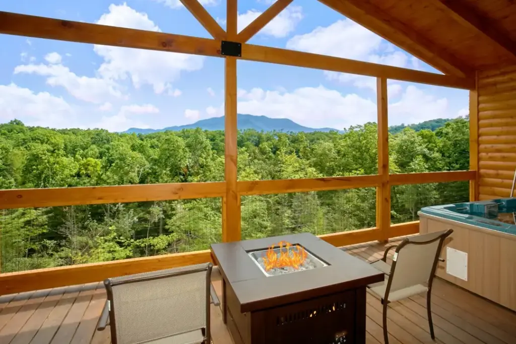 firepit in the middle of two chairs next to a private hot tub overlooking the smoky mountains