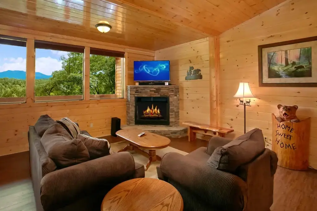 inside of gatlinburg cabin with fireplace and tv above it with couch and loveseat in the room