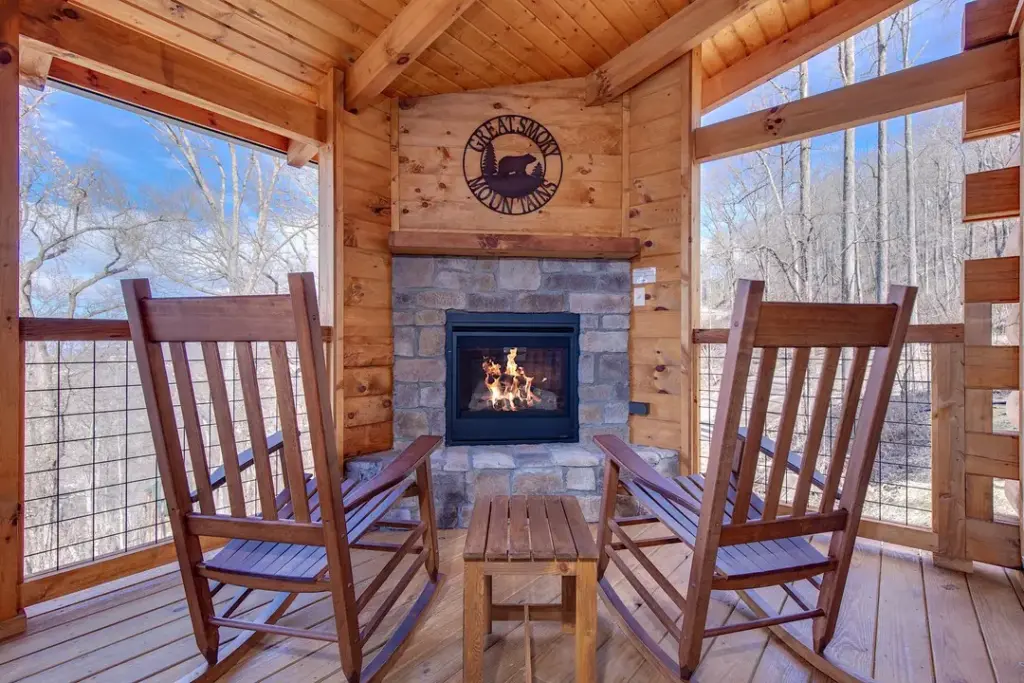 stone stacked fireplace with wooden rocking chairs and wooden table in the middle of them