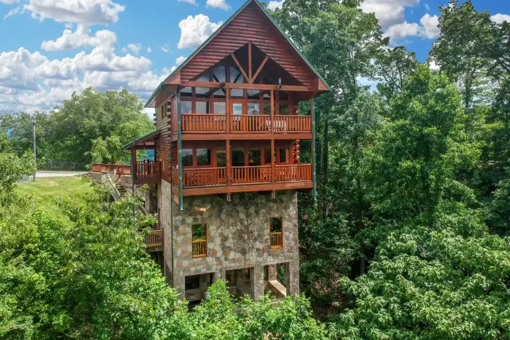 view of a multiple tiered cabin with balconies surrounded by trees