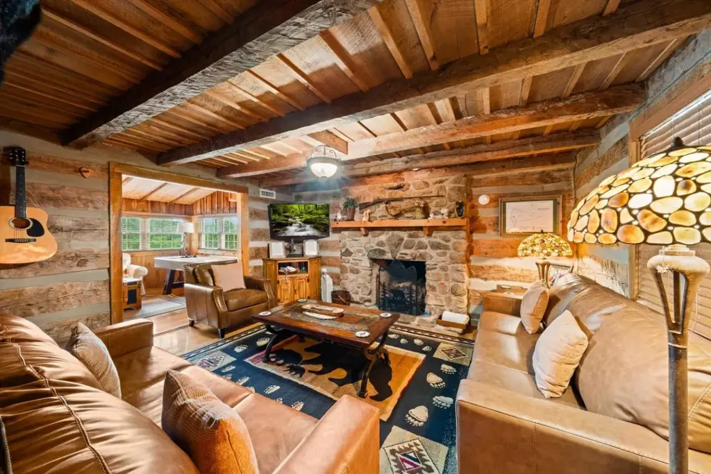 living room with tan couches, guitar, coffee table, and stone fireplace